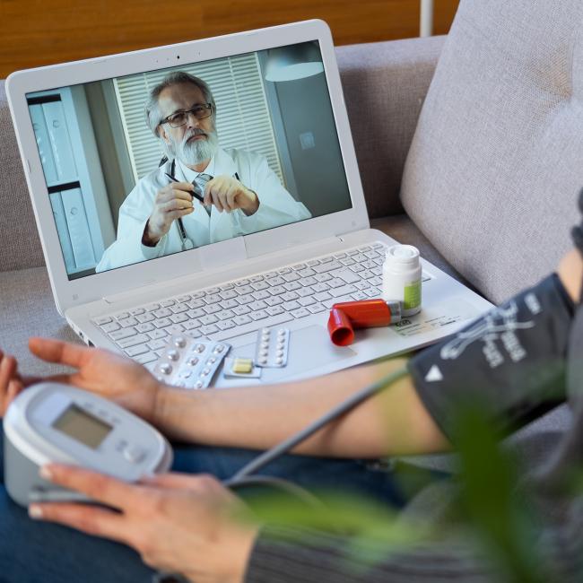 doctor appointment over a computer with patient taking their blood pressure